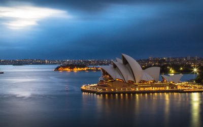 Sydney Opera House lit up on the harbour at dusk with the city skyline behind