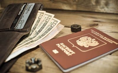 Passport, wallet, and dollar bills arranged on a wooden table