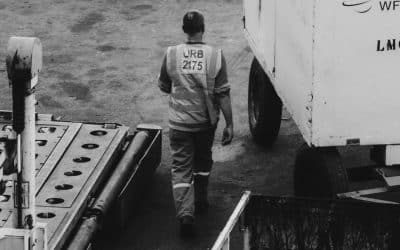 Airport ground crew member walking among cargo-handling equipment