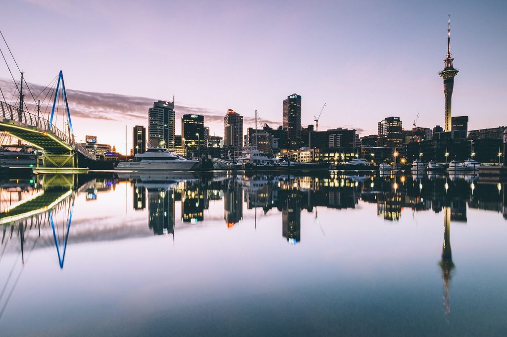 Auckland city skyline and Sky Tower reflected in the calm harbour water at dusk