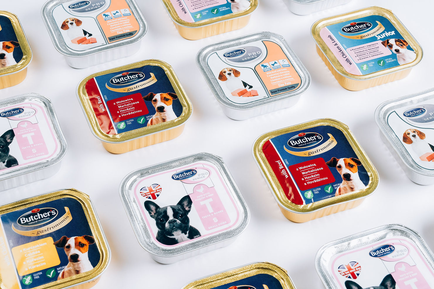 Many sealed trays of Butcher's brand wet dog food in different varieties arranged on a white surface
