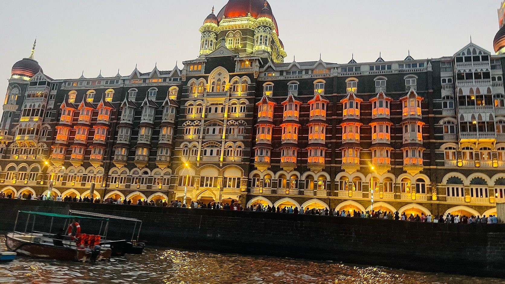 Illuminated Taj Mahal Palace hotel beside the waterfront in Mumbai at dusk