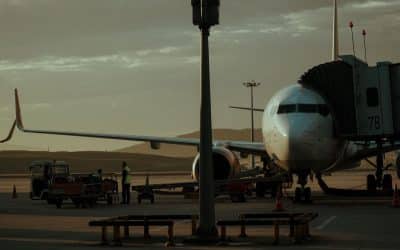 Commercial airplane at a gate while ground crew prepare for departure