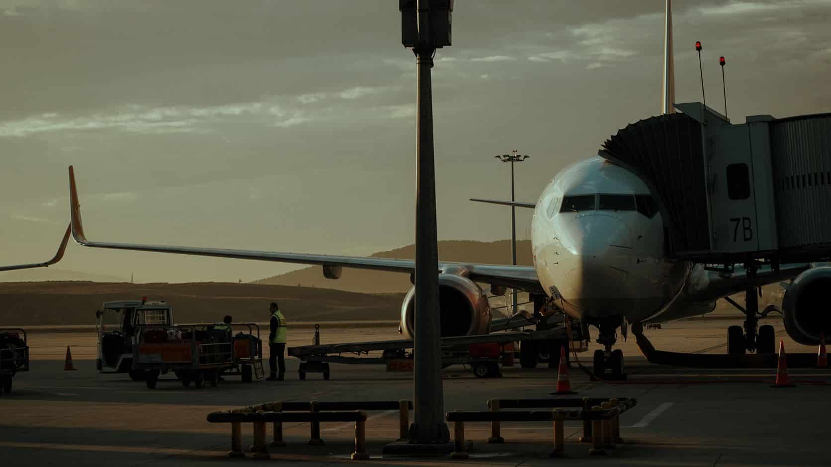 Commercial airplane at a gate while ground crew prepare for departure