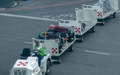 Airport ground crew member towing baggage carts across the tarmac